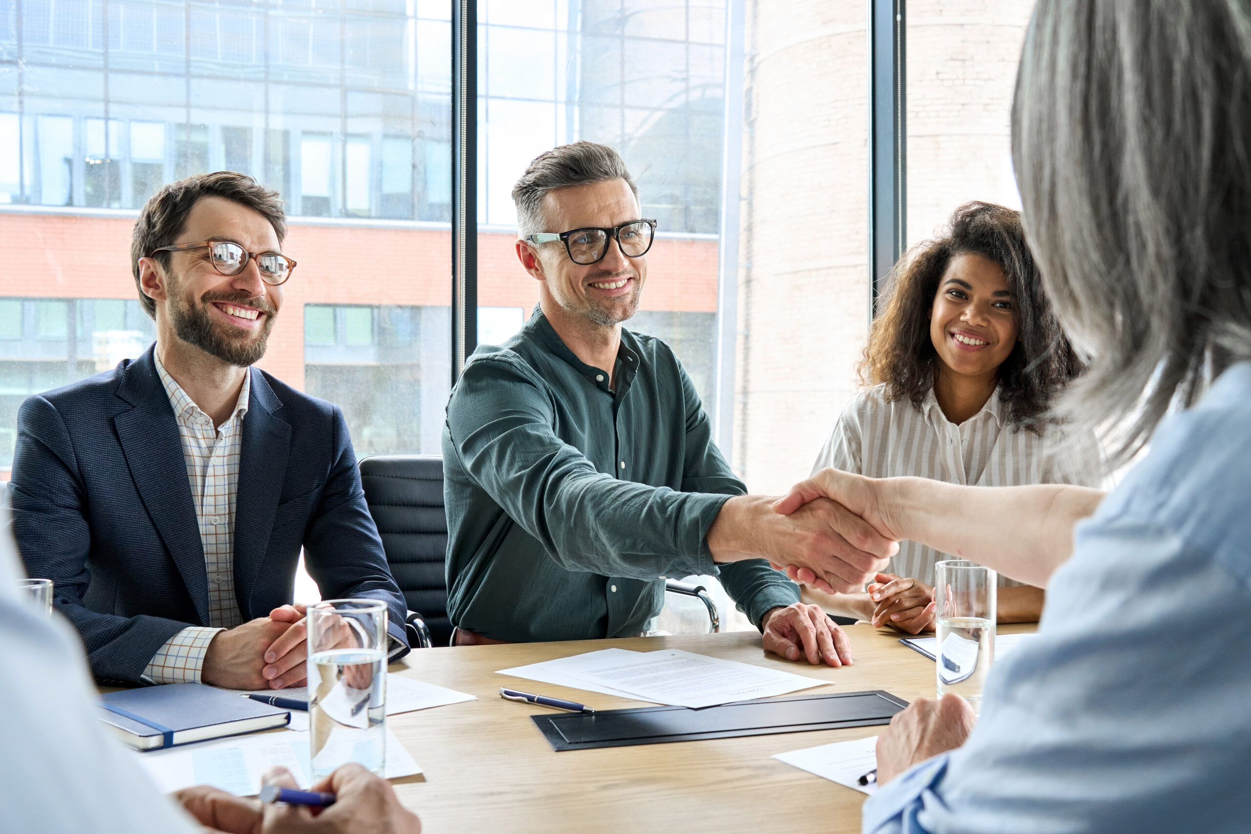a group of people sitting around a table shaking hands