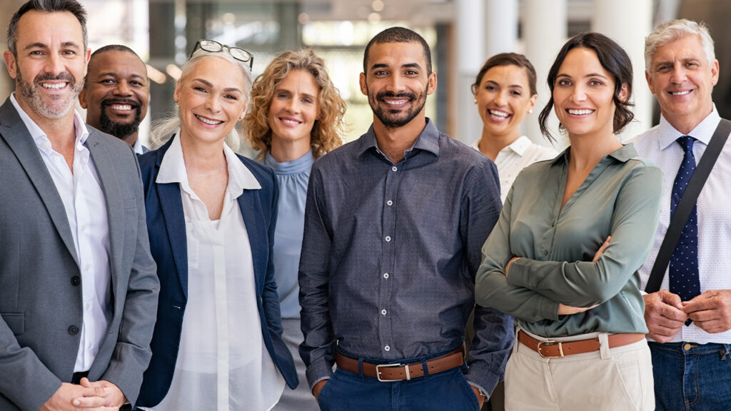 Diverse group of confident business professionals smiling in modern office setting, representing strong BPO-client relationships and rebuilding trust through collaboration.