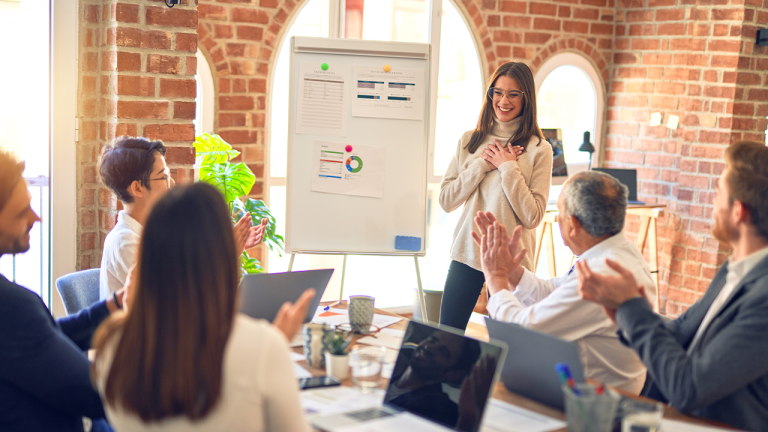 Team applauding a presenter in a modern office, discussing omnichannel retail strategies and customer experience improvements using data and analytics on a whiteboard.